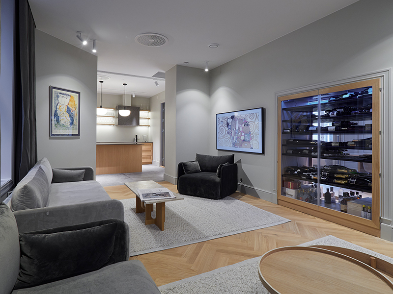 Stilfulle kontorlokaler i Pløens gate 1 med vinskap, grå lenestoler og moderne kjøkken i bakgrunnen.