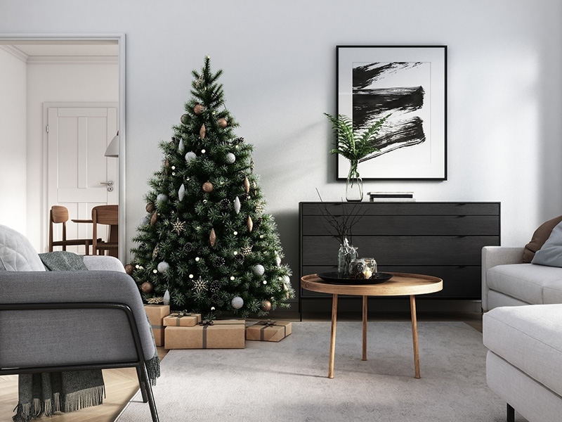 Bilde av et grønt juletre med glitter og julekuler. Står i en lys stue med store vinduer, snø utenfor.